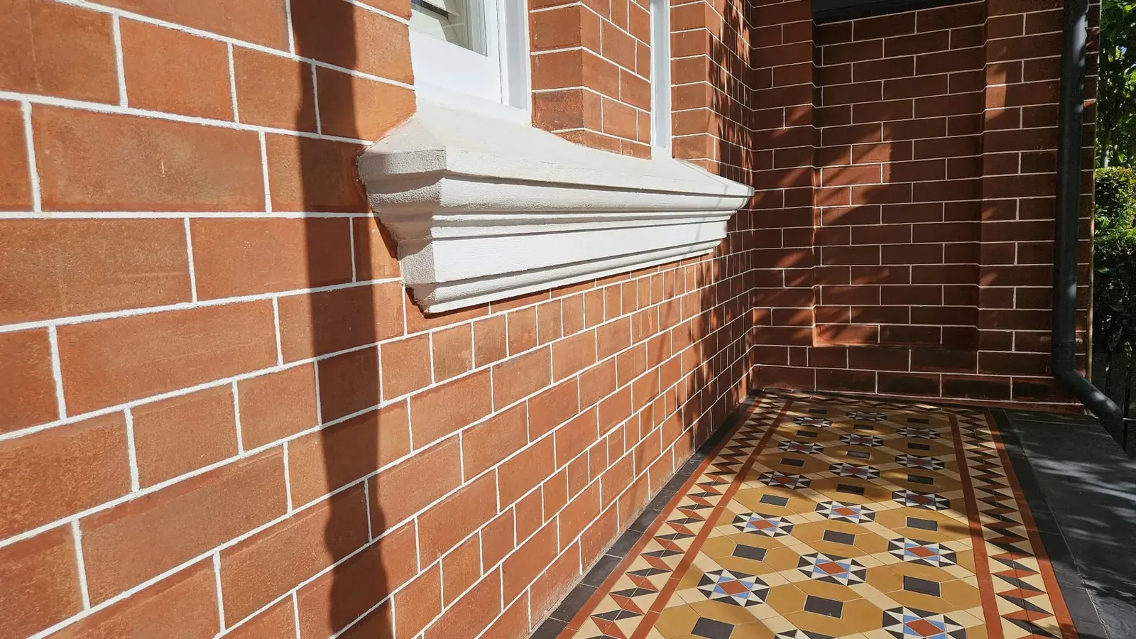 The new moulded sill under the front window after the work, above cleaned, tuckpointed red brick and the tessellated tiled porch.