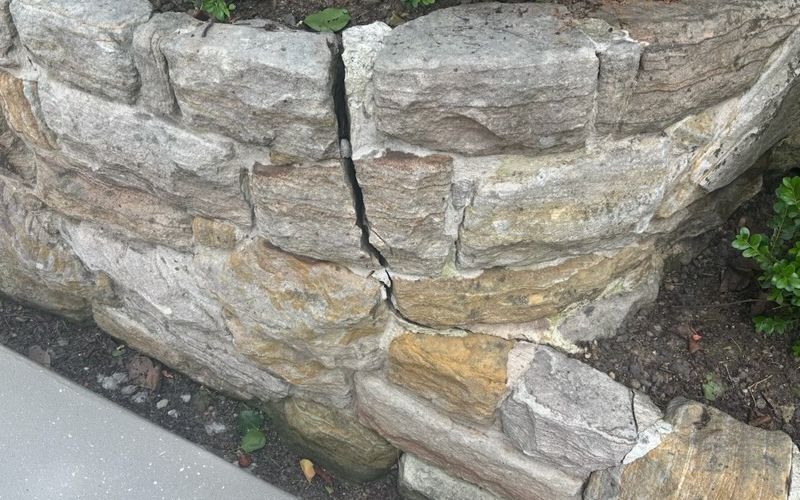 Cracking through a sandstone retaining wall, showing movement between the stone courses