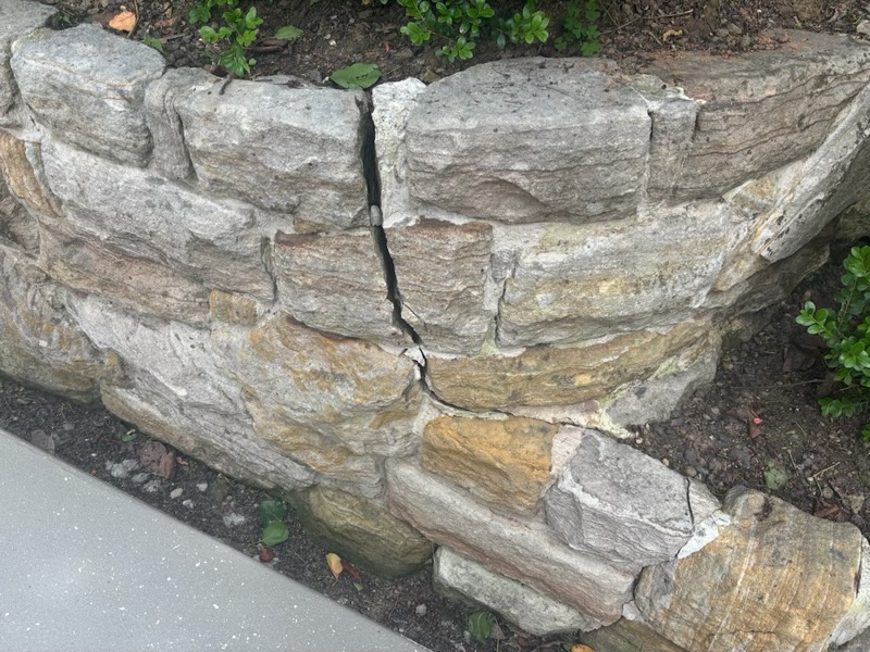 Cracking through a sandstone retaining wall, showing movement between the stone courses
