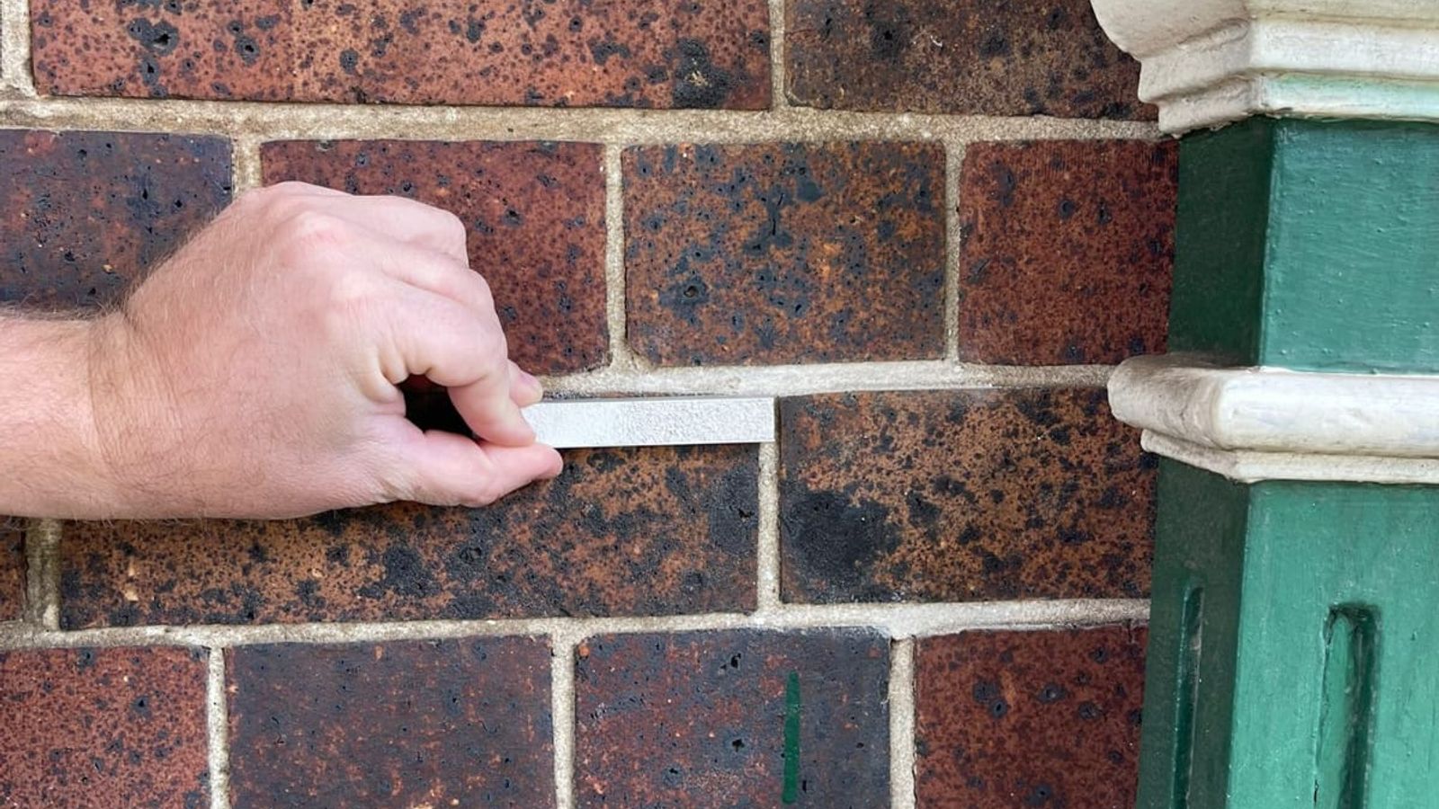 Checking a mortar sample against heritage brickwork during a repointing assessment