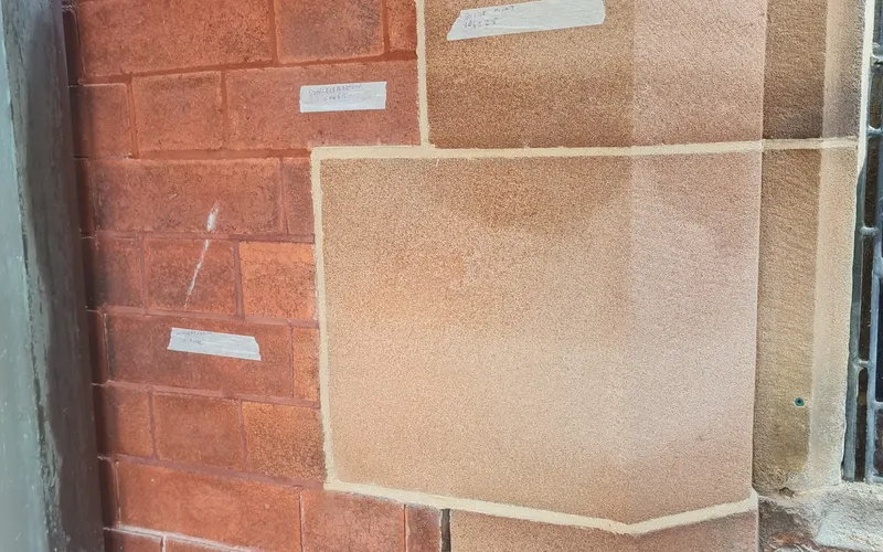Close-up of red brickwork beside sandstone blocks, showing mortar joints and labelled sample areas.