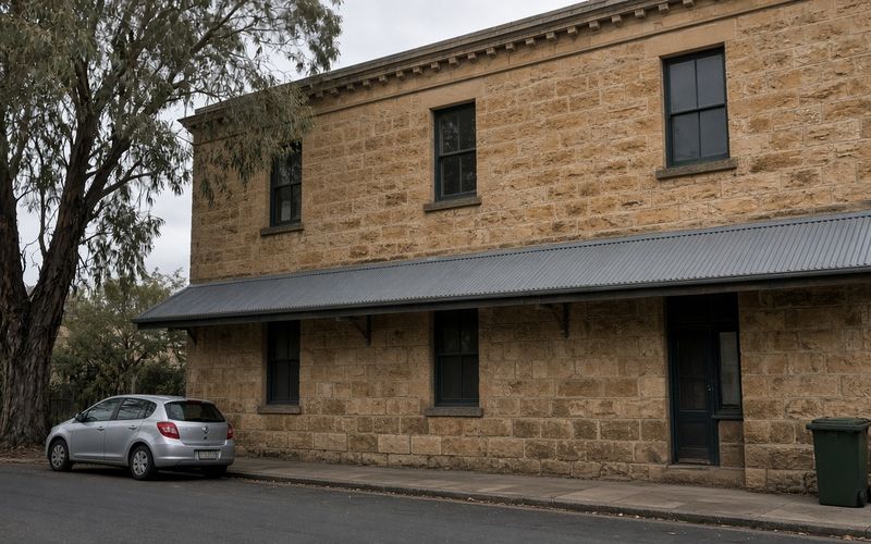 Two-storey sandstone building in Sydney with weathered base courses and matching replacement stone blocks