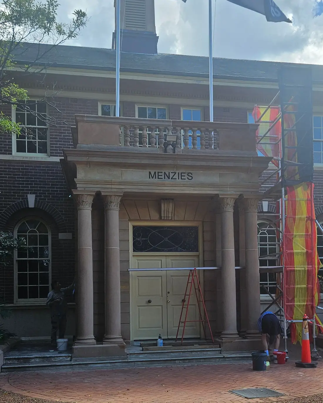 Heritage brick building with a sandstone entrance portico under scaffold during façade restoration