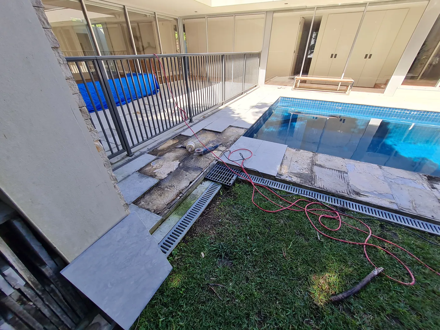 Pool surround mid-retiling with lifted pavers and exposed bed